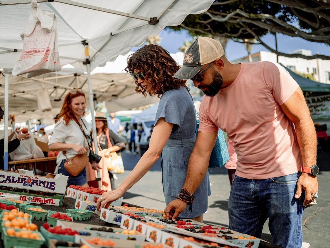 A man and a women inspecting produce at a farmers market