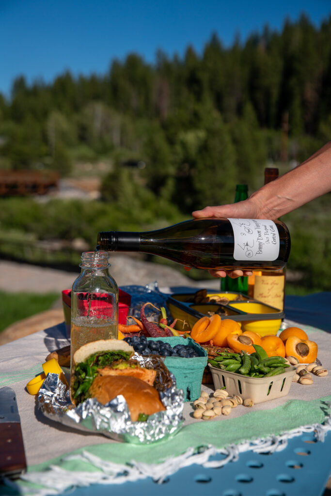 Spread of a picnic with apricots, peas, berries, nuts, and wine