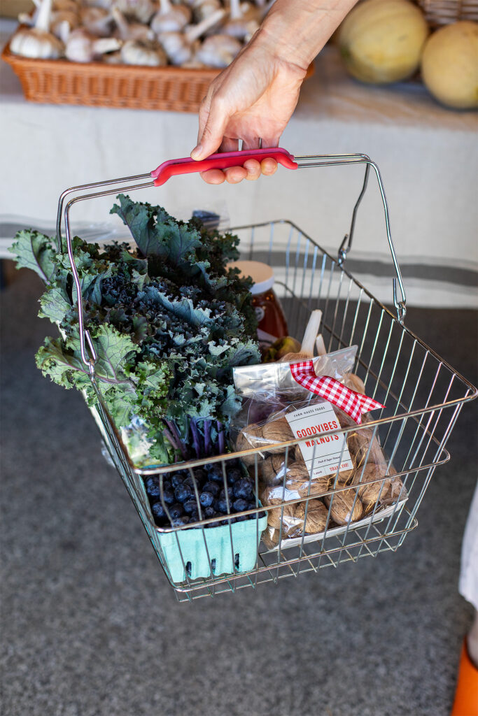 Metal shopping basket with kale, berries, and walnuts