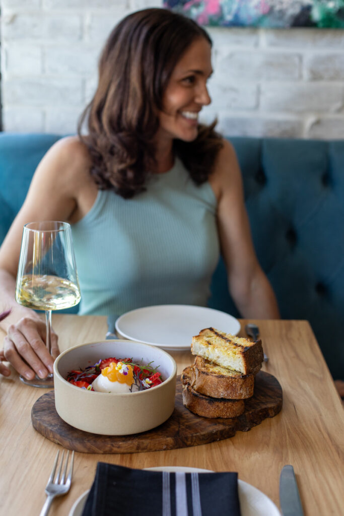 In boom table spread with woman holding glass of white wine
