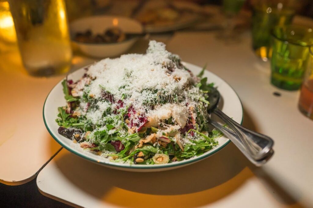 salad on white plate topped with shaved cheese