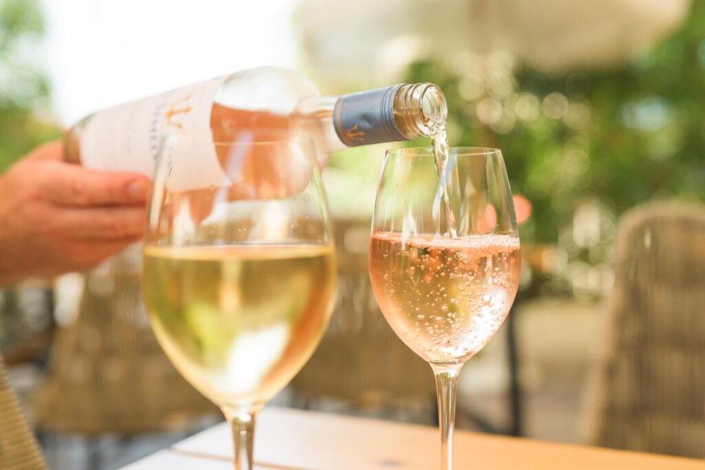 man pouring rose wine into glass